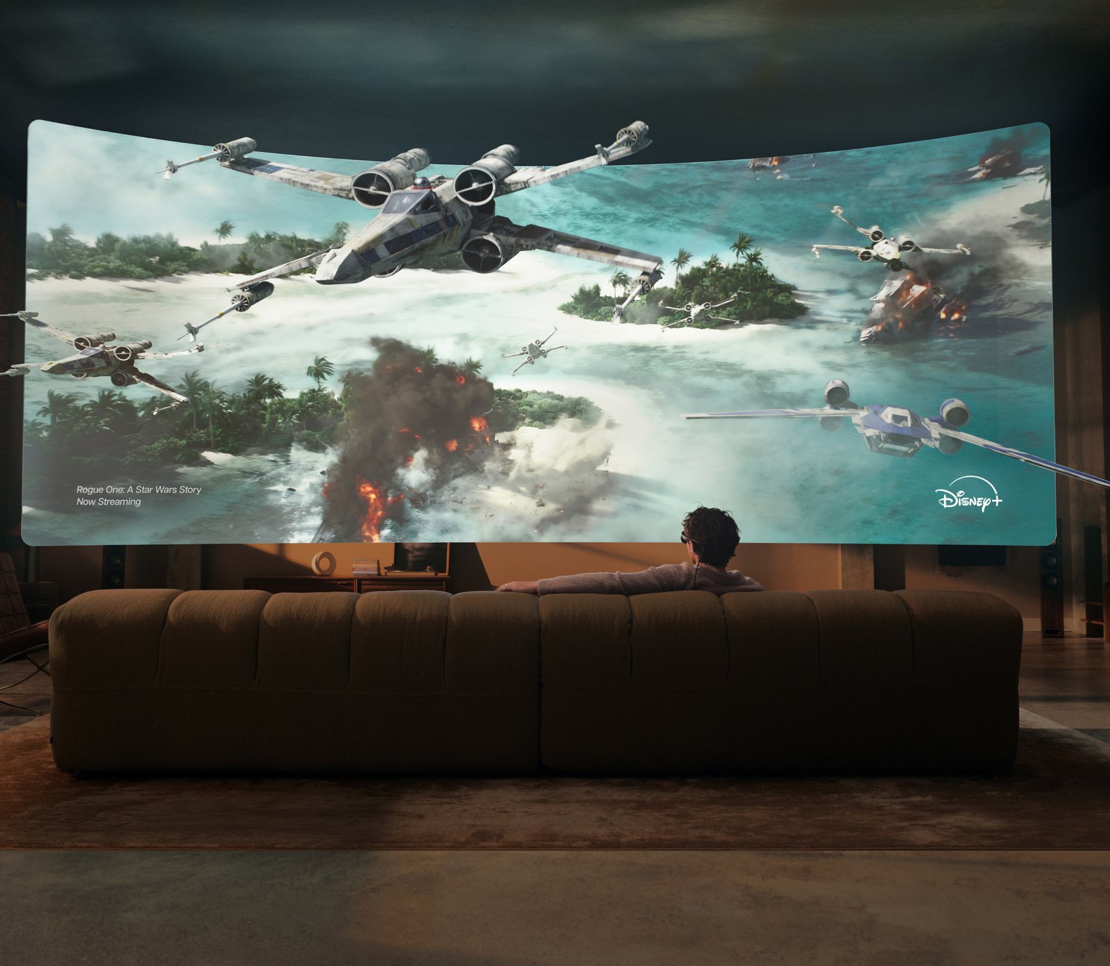 A person on a large sofa wearing Meta VR Glasses, watching a Star Wars battle scene on a giant curved virtual screen that fills the living room