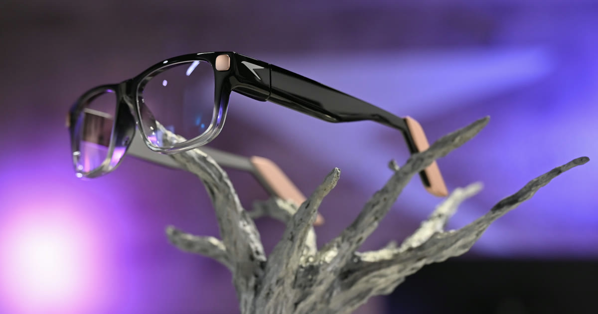 The Raven Prism ambient computer glasses on a sculptural display stand at AWE 2026, with rose gold accents and a clear lower frame