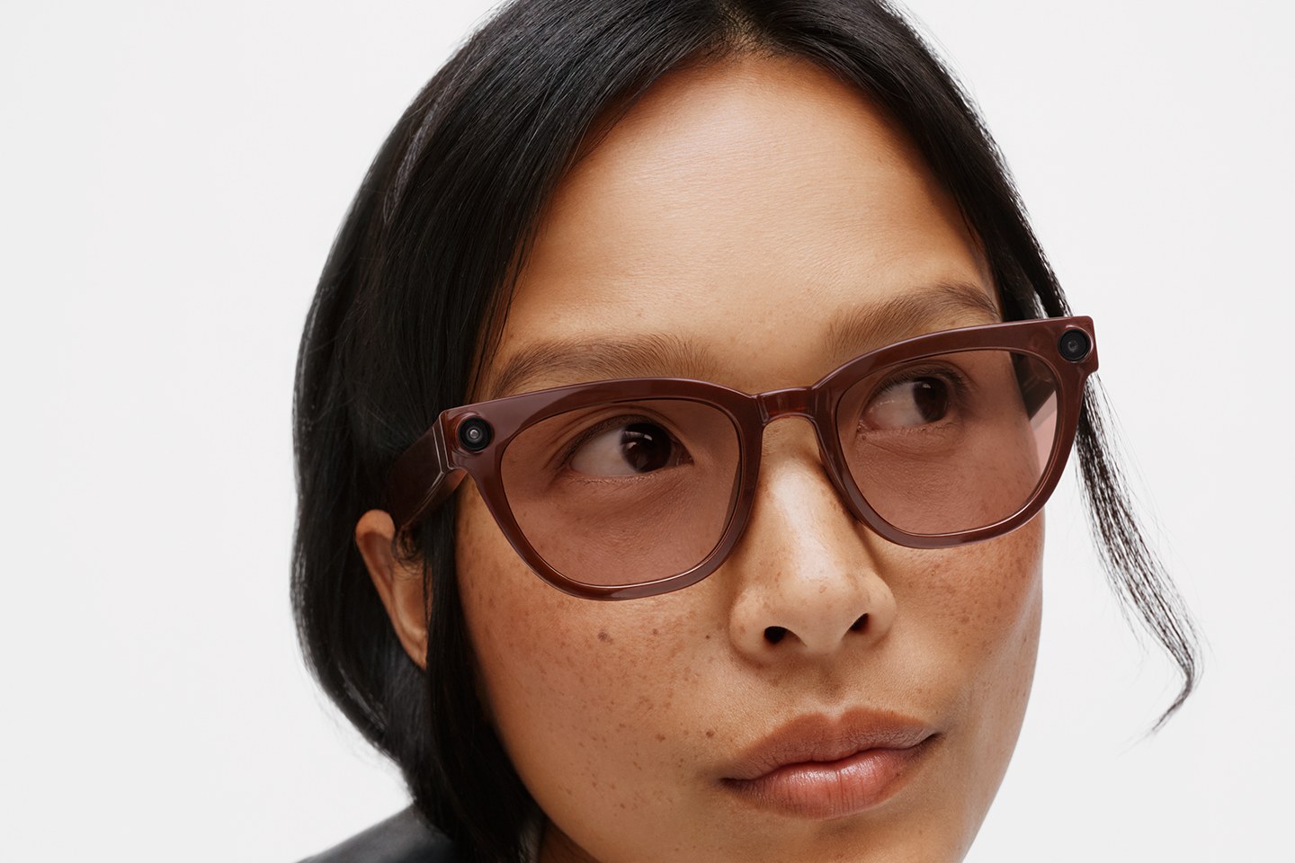 Close-up of a model wearing the brown Warby Parker frame of Samsung's Intelligent Eyewear, with a small round lens set into each front corner