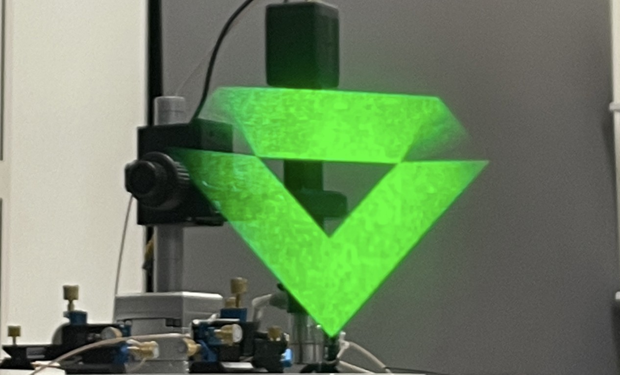 JBD's microLED projecting a bright green holographic test image on an optical bench during smart contact lens display development